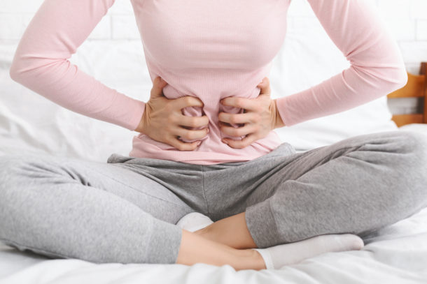 Menstrual pain. Woman suffering from abdominal pain, sitting in bed at home